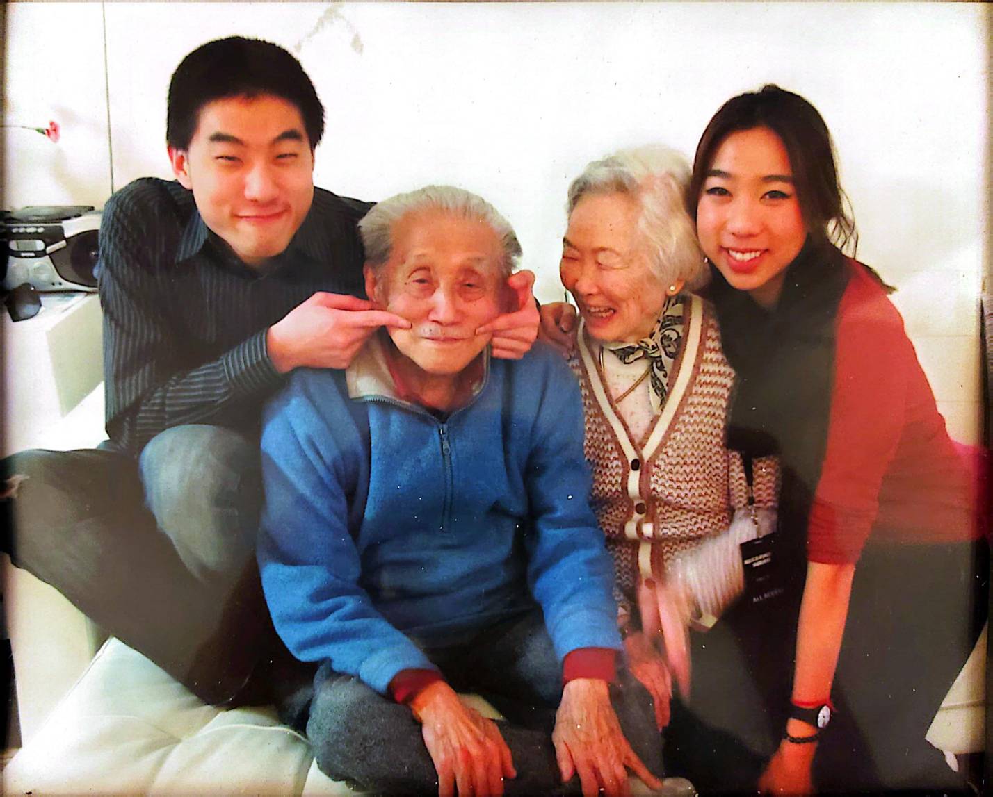 祖孫：這幅美麗的自然照片展示了丁大師與愛妻紀鳳被孫輩圍繞的溫馨時刻。這張照片捕捉了定義丁氏家風的輕鬆幽默與深厚情感。